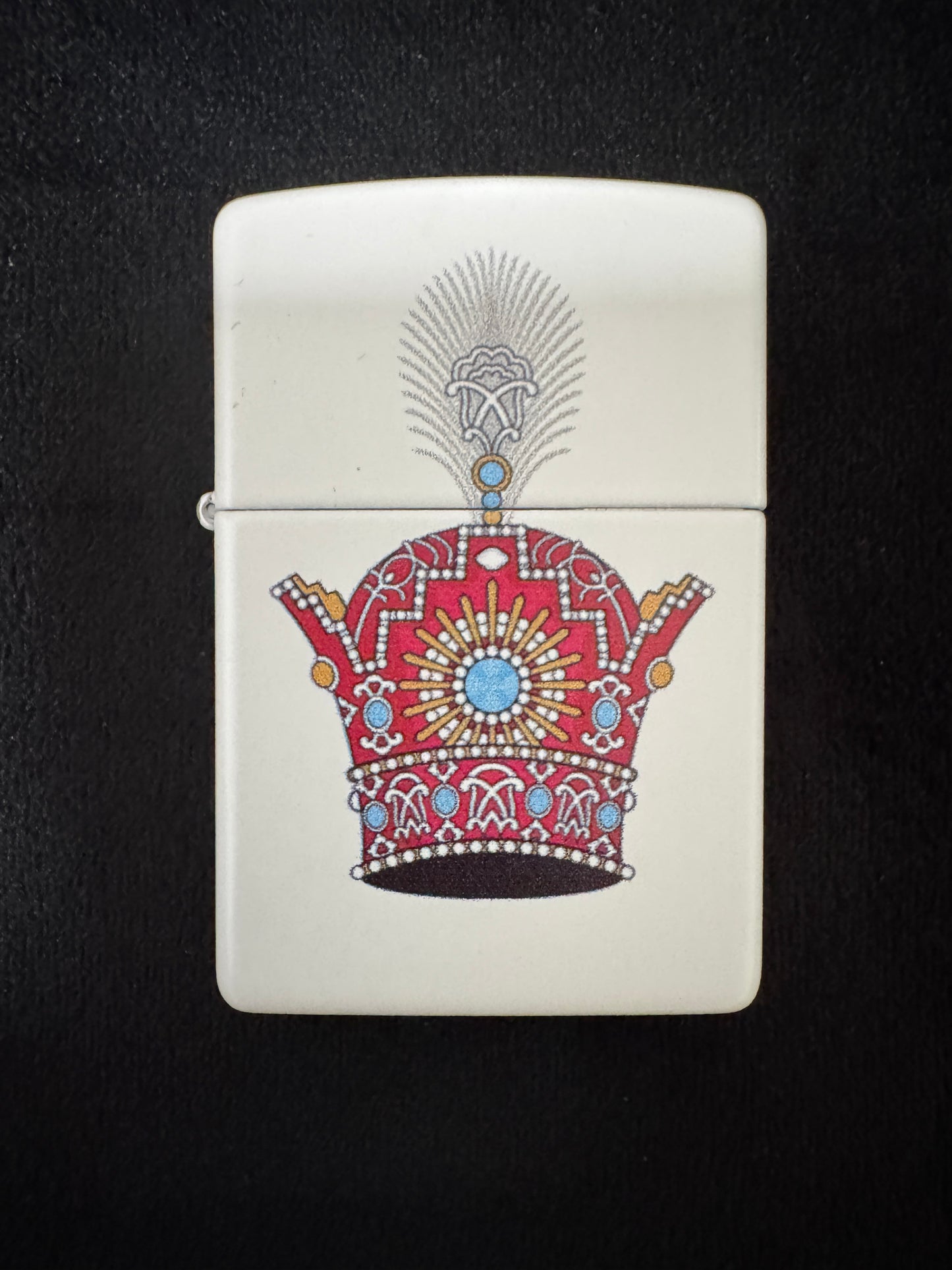 White lighter with red jeweled Pahlavi Crown design on black background