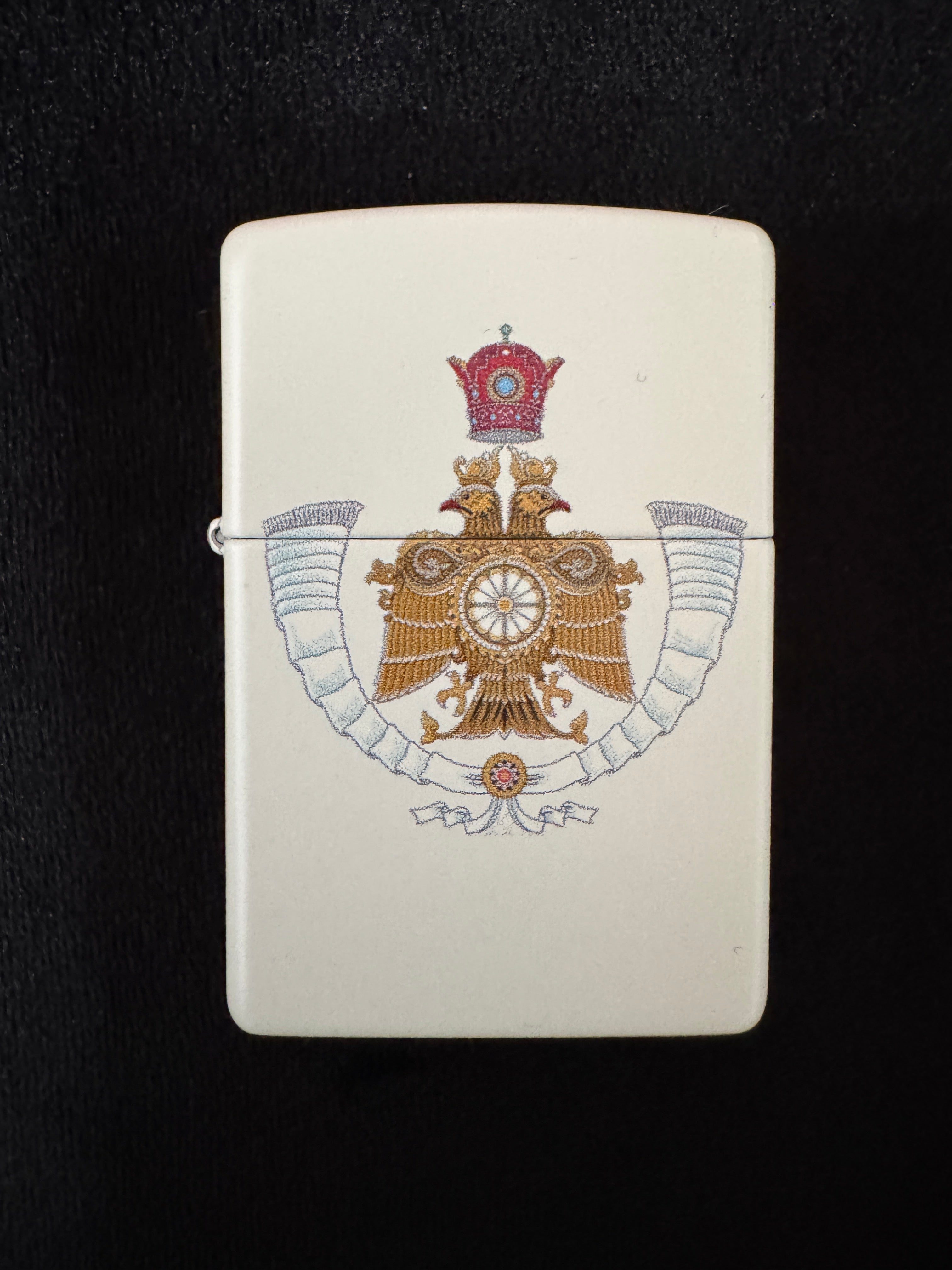 فندک سفید با طرح نشان ولیعهد شاهنشاهی ایران، تاج پهلوی و عقاب طلایی روی زمینه مشکی