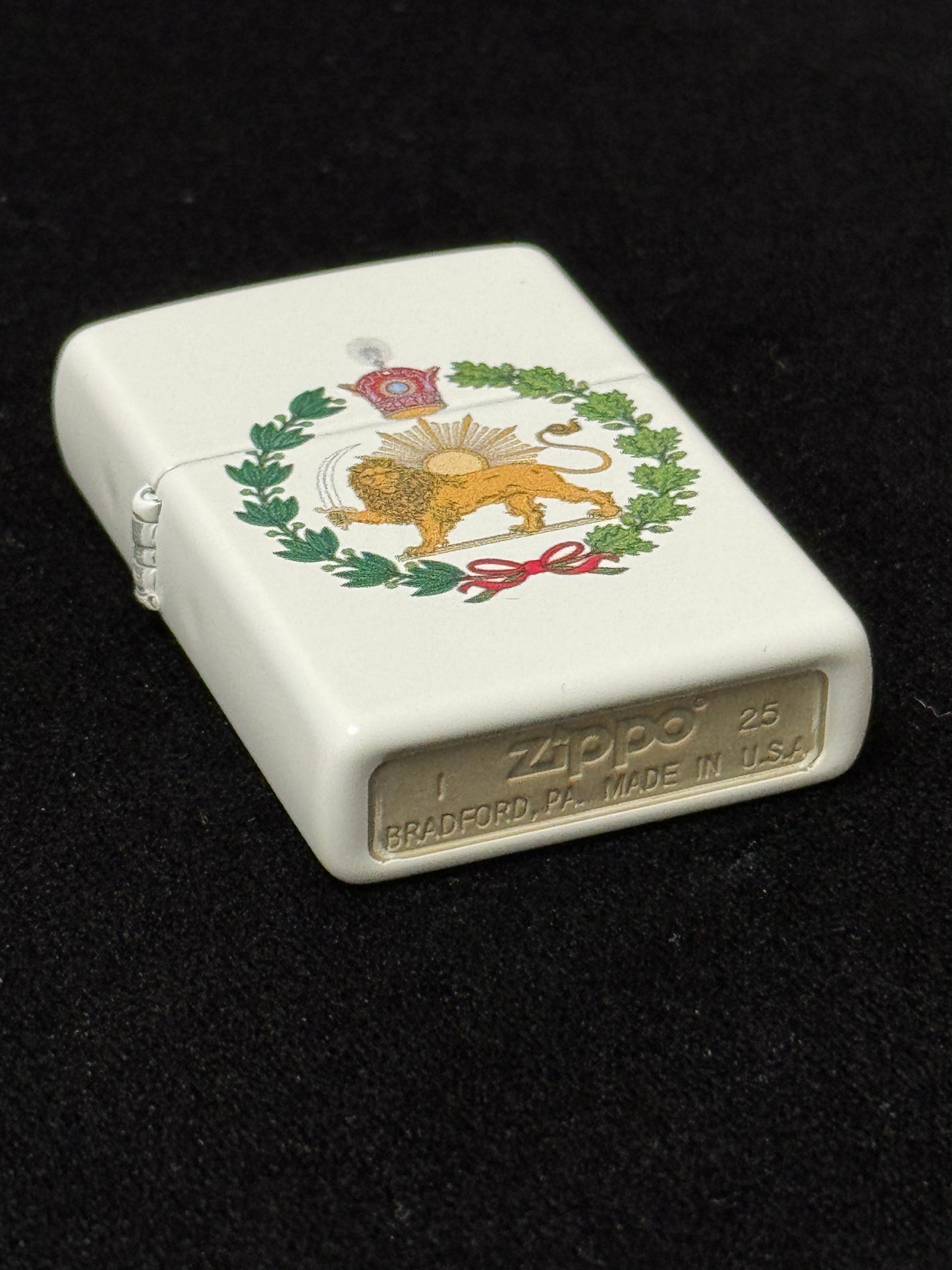 White lighter with a Crowned Lion and Sun emblem, Pahlavi Crown, and green wreath on a black background
