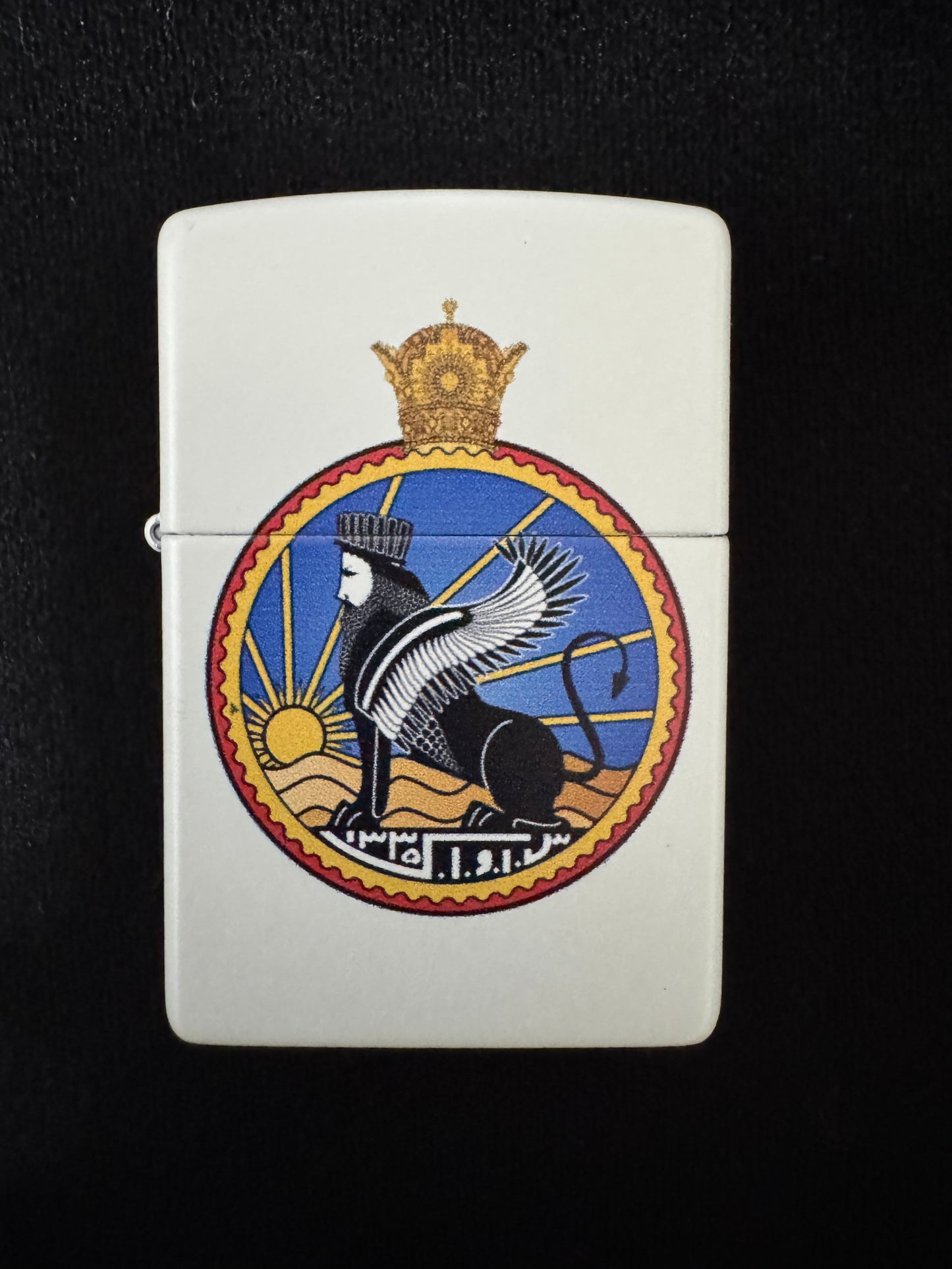 White lighter with SAVAK emblem, royal crown, and winged lion symbol on a black background